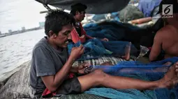 Sejumlah nelayan memperbaiki jaring di Pelabuhan Muara Angke, Jakarta, Kamis (27/12). Libur melaut dimanfaatkan nelayan untuk memperbaiki kapal dan jaring. (Liputan6.com/Faizal Fanani)