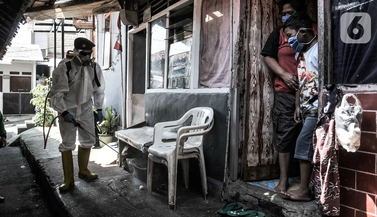 Warga menyaksikan petugas PMI Jakarta Timur  menyemprotkan disinfektan di permukiman Kampung Tengah, Kramat Jati, Minggu (23/8/2020). Penyemprotan sebagai langkah sterilisasi permukiman setelah warga di Kampung Tengah dilaporkan terpapar Covid-19. (Liputan6.com/Iqbal Nugroho)