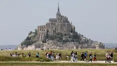 Orang-orang berjalan melewati Biara Mont-Saint-Michel saat kunjungan Presiden Prancis Emmanuel Macron di Normandia, Le Mont-Saint-Michel, Prancis, Senin (5/6/2023). (Ludovic MARIN/POOL/ AFP)