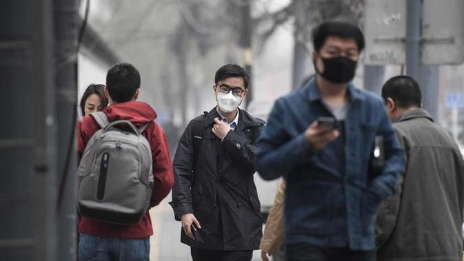 Sejumlah warga mengenakan masker wajah berjalan menyusuri jalan pada hari yang tercemar polusi di Beijing, China (2/4). (AFP Photo/Fred Dufour)