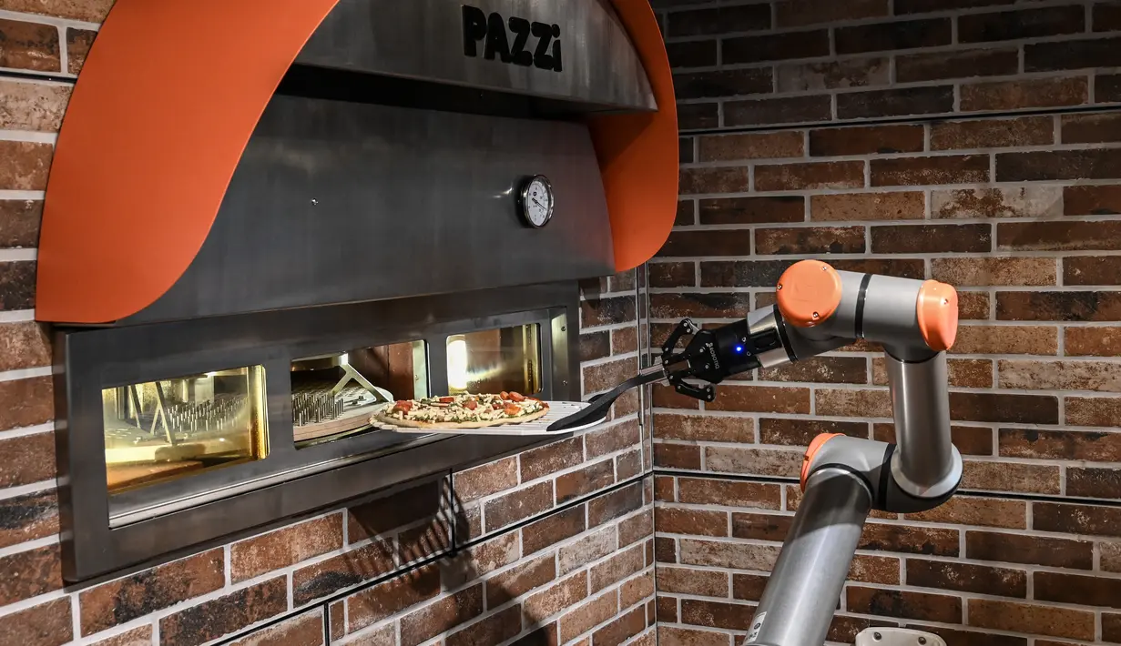 Robot pembuat pizza Bernama "Pazzi" sedang bekerja di sebuah restoran di Paris pada 1 Juli 2021. Pelanggan cukup memesan melalui sebuah terminal atau aplikasi dan memilih pizza yang diinginkan dan menentukan waktu pengambilan. (BERTRAND GUAY/AFP)