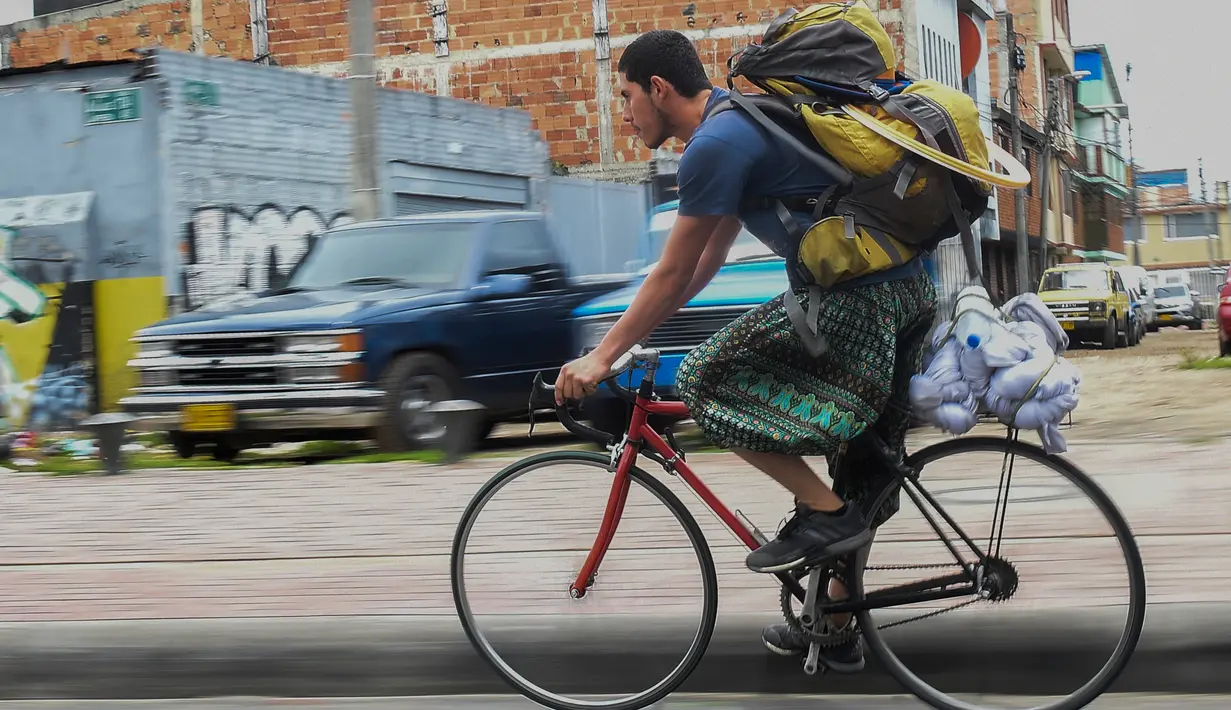 Jahn Fredy Duque bersepeda menuju tempat beraksinya di jalanan Bogota, Kolombia, Senin (24/4). Duque mencari nafkah dengan melakukan atraksi layaknya Spiderman. (AFP Photo/RAUL ARBOLEDA)