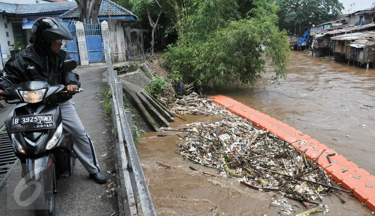 Warga melihat tumpukan sampah yang tertahan di dekat pintu air Manggarai, Jakarta, Rabu (8/3). Hujan deras yang mengguyur kawasan Jabodetabek semalam membuat aliran air Ciliwung meningkat dan membawa sampah. (Liputan6.com/Yoppy Renato)