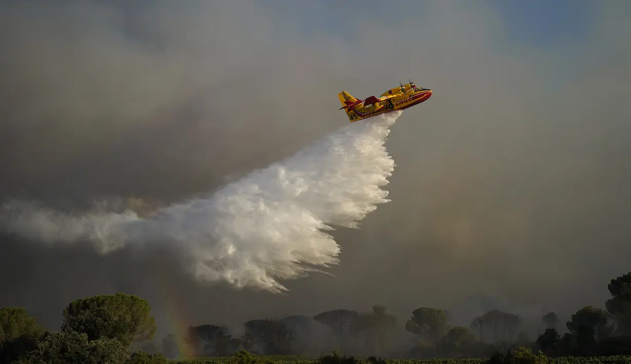 Sebuah pesawat pembuangan air membuang air ke api di dekat Le Luc, Prancis selatan, Selasa (17/8/2021). Kebakaran hutan mengirimkan asap yang mengepul menuruni lereng berhutan menuju kebun anggur di daerah yang indah. (AP Photo/Daniel Cole)