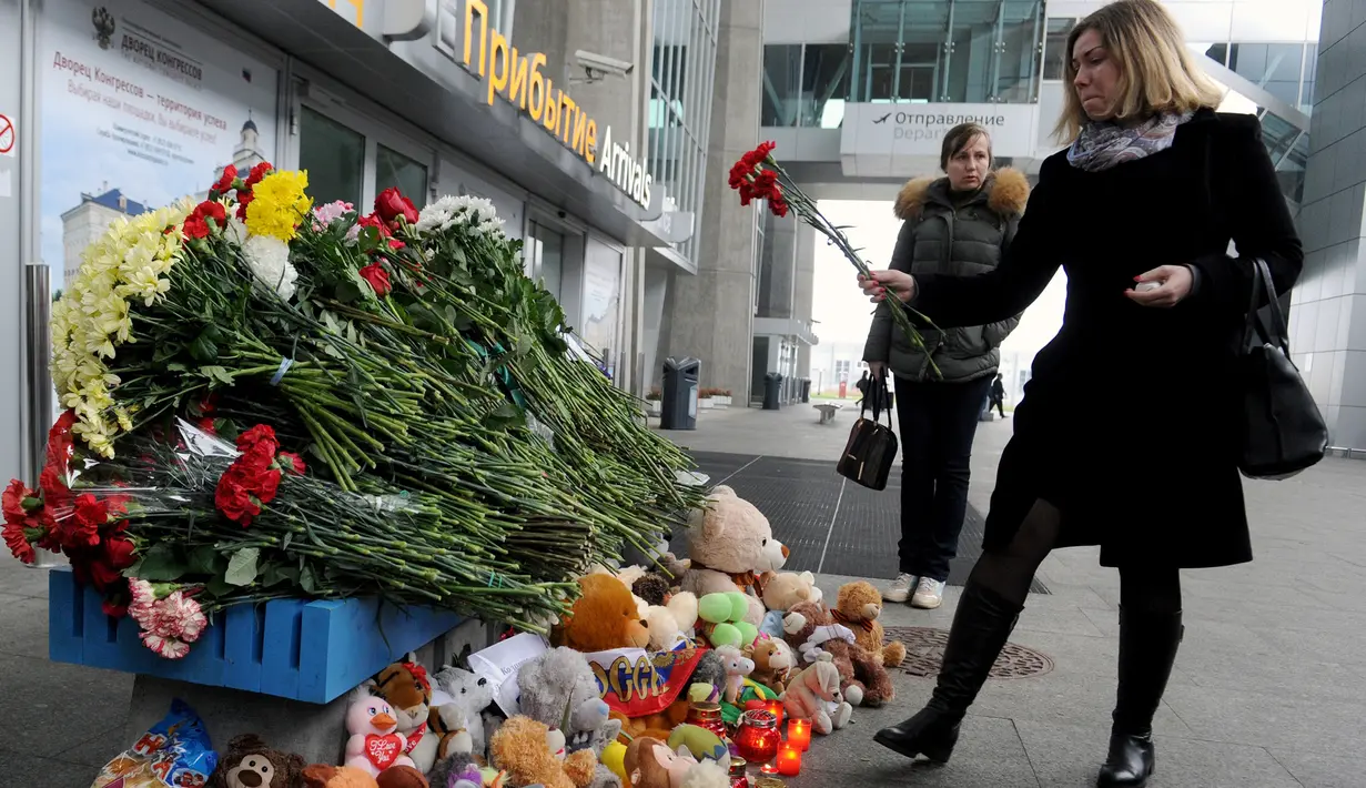 Seorang wanita meletakkan bunga di depan Bandara Internasional St. Petersburg di Rusia, Minggu (1/11). ini sebagai bentuk penghormatan kepada para penumpang yang menjadi korban jatuhnya pesawat Kogalymavia di Mesir. (AFP PHOTO/OLGA MALTSEVA)