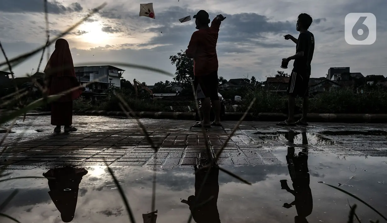 Anak-anak bermain layang terlihat dari refleksi air Waduk Kampung Rambutan 2, Jakarta, Kamis (12/11/2020). Beragam kegiatan seperti olahraga, memancing, dan bermain layang-layang menjadi pemandangan di waduk ini saat sore hari. (merdeka.com/Iqbal S. Nugroho)