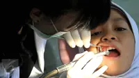 Dokter memeriksa gigi seorang siswa di Fakultas Kedokteran Gigi Moestopo, Jakarta, Senin (23/11/2015). Bulan Kesehatan Gigi Nasional bertujuan untuk mengedukasi mengenai pentingnya merawat kesehatan gigi. (Liputan6.com/Johan Tallo) 