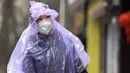 Seorang perempuan bermasker mengenakan jas hujan membawa bahan makanan untuk melindungi diri dari wabah virus corona di Wuhan, China, 10 Februari 2020. Awal tahun 2020 ini, masyarakat dunia dikejutkan dengan hadirnya virus corona COVID-19 yang mematikan asal Wuhan, China. (Chinatopix via AP)