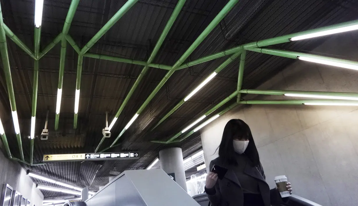 Seorang wanita yang mengenakan masker pelindung untuk membantu mengekang penyebaran virus corona mengendarai eskalator di stasiun kereta bawah tanah di Tokyo, Selasa (26/1/2021). Jepang mengonfirmasi lebih dari 1.000 kasus Virus Corona baru pada 26 Januari 2021. (AP Photo/Eugene Hoshiko)