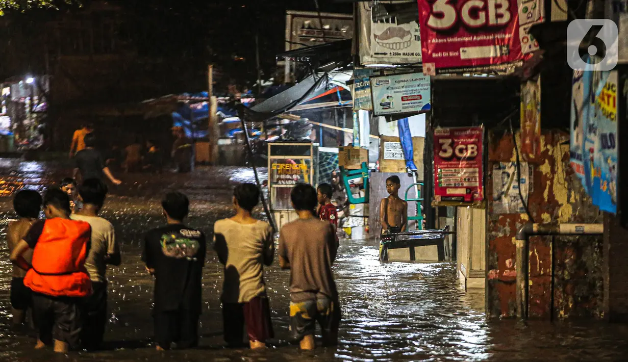 Sejumlah warga melintasi genangan banjir di kawasan Kemang, Jakarta, Selasa (4/10/2022). Jalan Kemang Utara IX tak bisa dilalui oleh kendaraan. Banjir menggenangi kawasan Pasar Kambing dan sejumlah rumah penduduk. (Liputan6.com/Faizal Fanani)
