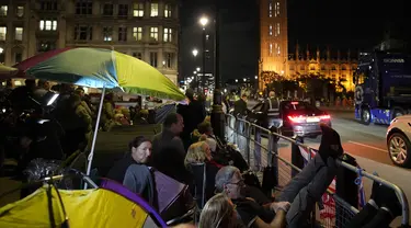 Orang-orang berkemah di depan Istana Westminster pada malam pemakaman Ratu Elizabeth II di London, Minggu, 18 September 2022. Pemakaman Ratu Elizabeth II, raja terlama di Inggris, berlangsung pada Senin (19/9). (AP/Christophe Ena)