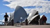 Warga berjalan dekat Gedung Opera di Sydney, Australia, Sabtu (26/6/2021). Pihak berwenang melakukan lockdown beberapa area pusat kota terbesar di Australia untuk menantisipasi penyebaran virus corona COVID-19 varian Delta yang sangat menular. (Saeed KHAN/AFP)