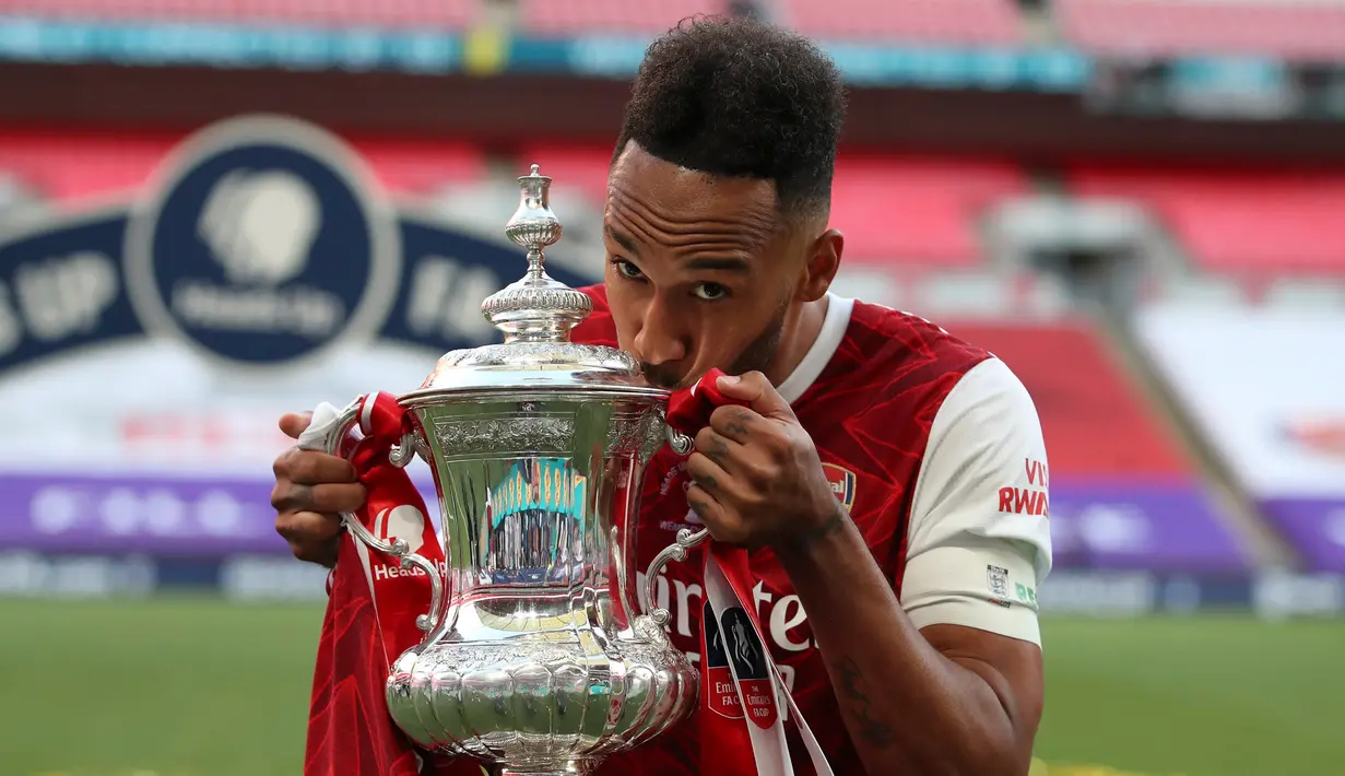 Striker Arsenal, Pierre-Emerick Aubameyang mencium trofi saat merayakan gelar juara Piala FA setelah mengalahkan Chelsea pada pertandingan final Piala FA di stadion Wembley, Minggu (2/8/2020).  Aubameyang menjatuhkan trofi saat prosesi selebrasi. (Adam Davy/Pool via AP)