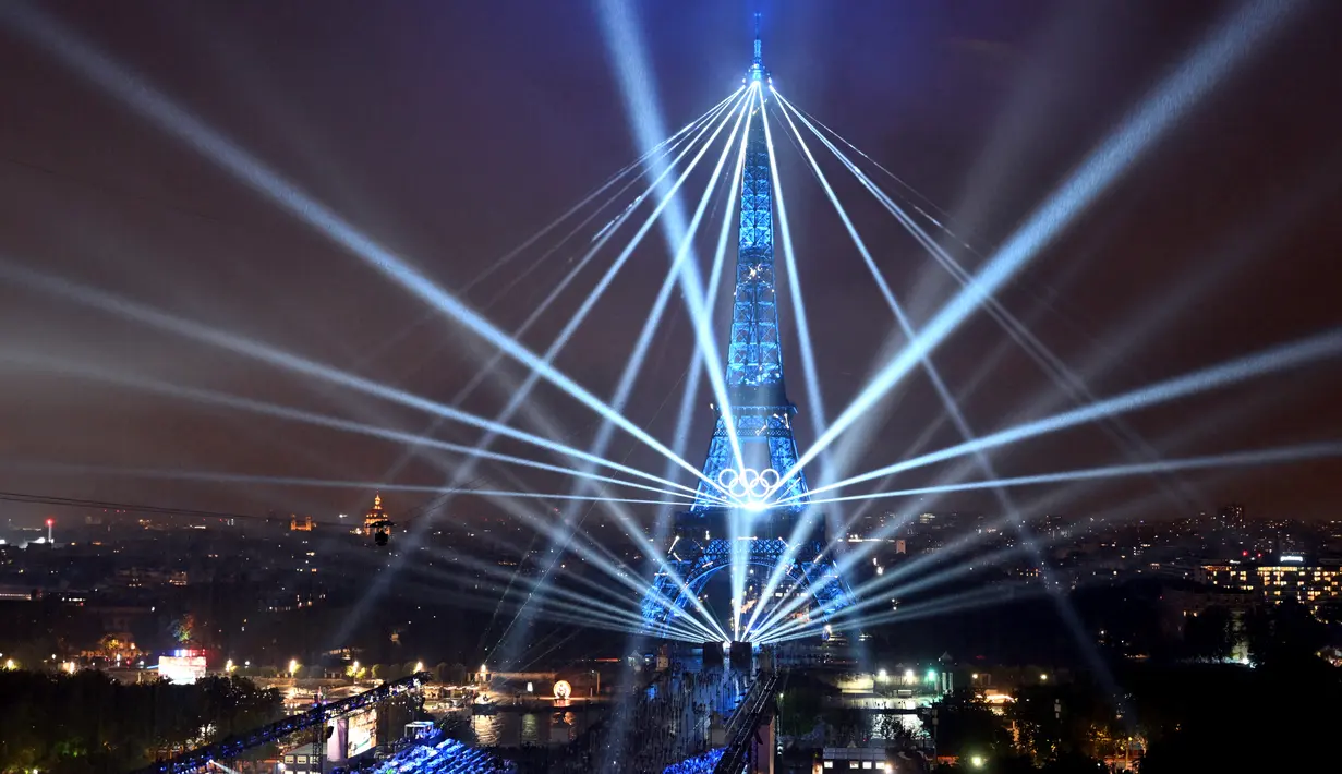 Pemandangan Menara Eiffel dan laser yang menerangi langit, selama upacara pembukaan Olimpiade Paris 2024, Jumat (26/7/2024). (Cheng Min / POOL / AFP)