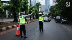 Petugas kepolisian mengarahkan kendaraan saat pengalihan arus di Jalan Jenderal Sudirman, Jakarta, Minggu (31/12). Pengalihan terkait malam puncak perayaan pergantian tahun di kawasan Bundaran HI hingga Jalan MH Thamrin. (Liputan6.com/Helmi Fithriansyah)