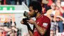 Penyerang Liverpool, Mohamed Salah, mencium trofi Sepatu Emas Premier League usai laga melawan Brighton & Hove Albion di Stadion Anfield, Minggu (13/5/2018). Salah menjadi top scorer Premier League musim ini dengan raihan 32 gol. (AFP/Paul Ellis)