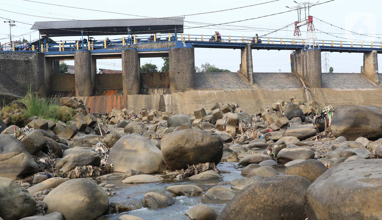 Warga berkendara motor melintasi Bendung Katulampa, Kota Bogor, Jawa Barat, Senin (3/8/2020). Debit air sungai Ciliwung di Bendung Katulampa mengalami penyusutan sejak satu bulan terakhir memasuki awal musim kemarau dengan ketinggan air 0 cm. (Liputan6.com/Helmi Fithriansyah)