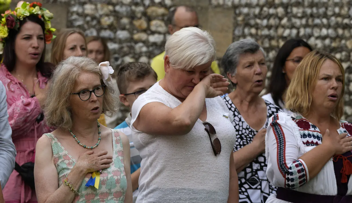 Pengungsi Ukraina bereaksi saat lagu kebangsaan dimainkan dalam perayaan Hari Kemerdekaan Ukraina di Chichester, Inggris selatan, Sabtu, 27 Agustus 2022. Chichester dinobatkan sebagai daerah paling dermawan di negara itu untuk menampung pengungsi Ukraina. (AP Photo/Frank Augstein)