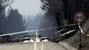 Garis polisi terpasang dekat mobil yang hangus di tengah jalan antara Castanheira de Pera dan Figueiro dos Vinhos, Portugal, Minggu (18/6). Ada kekhawatiran korban jiwa masih akan bertambah mengingat sejumlah orang masih hilang. (AP Photo/Armando Franca)