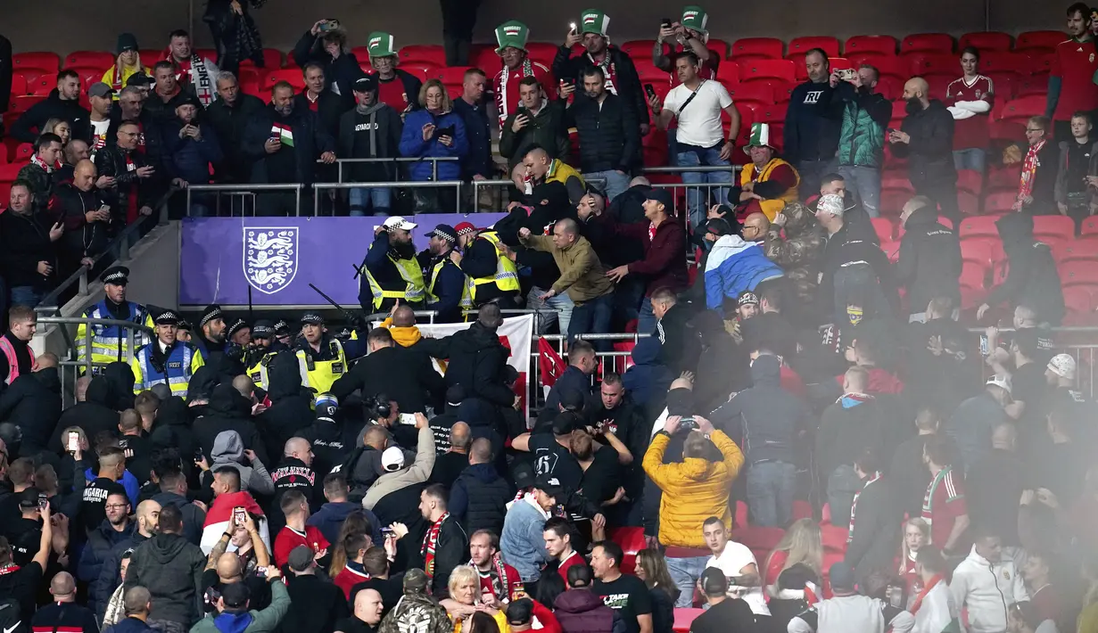 Suporter Hungaria bentrok dengan polisi saat dimulainya laga Kualifikasi Piala Dunia 2022 melawan Inggris di Stadion Wembley, Rabu (13/10/2021) dini hari WIB. Bentrokan terjadi saat polisi berusaha menangkap penonton yang melakukan pelecehan rasial terhadap petugas stadion. (Nick Potts/PA via AP)