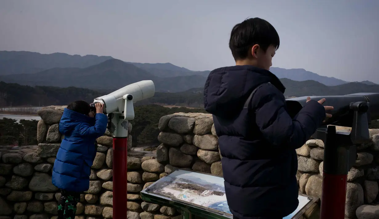 Dua anak laki-laki melihat teropong di atap vila yang dikenal sebagai Kastil Hwajinpo di Pantai Hwajinpo, Korea Selatan, (19/2). Villa ini termasuk dalam wilayah Korea Utara sebelum perang tahun 1950- 53. (AP Photo/Jae C. Hong)
