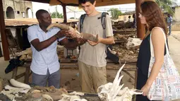 Seorang turis memegang tanduk saat sedang mengunjungi pasar jimat Akodessewa di Togo, Afrika, 5 Agustus 2015. Pasar ini menjual berbagai benda-benda klenik dan juga peralatan sihir. (AFP PHOTO/EMILE KOUTON) 