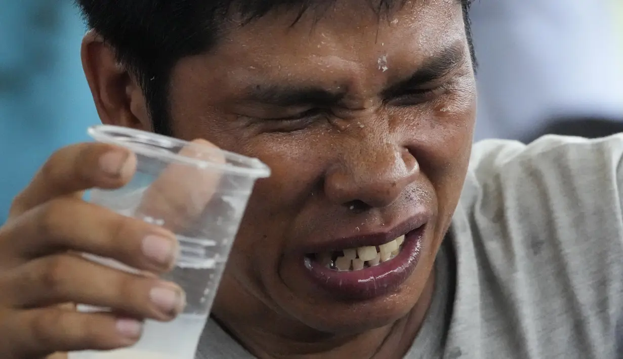 Seorang pria yang kepedasan mencoba meredakannya dengan meminum air. (AP Photo/Aaron Favila)