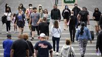 Pejalan kaki dengan masker dan tanpa masker berjalan di sepanjang Las Vegas Strip, di Las Vegas Selasa (27/4/2021). Warga Amerika Serikat (AS) yang telah menerima vaksin COVID-19 tidak lagi diwajibkan mengenakan masker saat berada di luar ruangan jika tidak ada kerumuman. (AP Photo/John Locher)