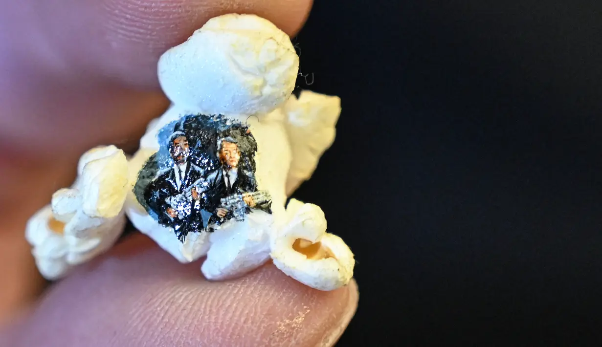 Popcorn bergambar dua pria bersenjata berpakaian hitam karya seniman mikro Hasan Kale, Istanbul, Turki, 23 Agustus 2019. Seniman mikro Turki menjadikan popcorn hingga lipstik sebagai kanvas lukis yang menakjubkan. (OZAN KOSE/AFP)