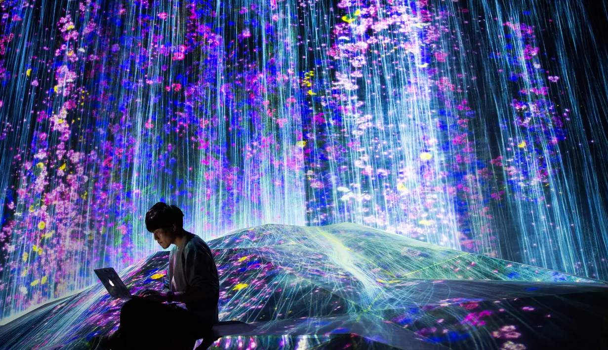 Anggota Teamlab Jepang bekerja menggunakan laptopnya di ruang instalasi digital air terjun di Mori Building Digital Museum Seni, Tokyo, Jepang (1/5). (AFP Photo/Behrouz Mehri)