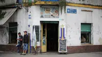 Dua orang pria berdiri di luar restoran Ribera Sur di lingkungan La Boca, ibu kota Argentina, Buenos Aires pada 27 November 2018. La Boca merupakan salah satu pusat kebudayaan dan wisata di Buenos Aires. (Ludovic MARIN / AFP)