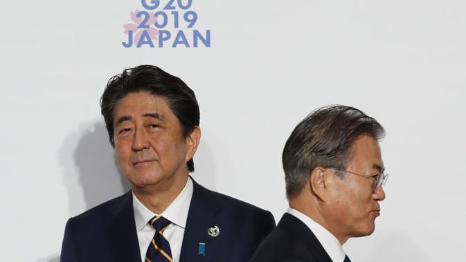 Presiden Korea Selatan (kiri) berjabat tangan dengan Perdana Menteri Jepang Shinzo Abe (kanan) di KTT G-20 tahun 2019 (AFP/Kim Kyung-Hoon)