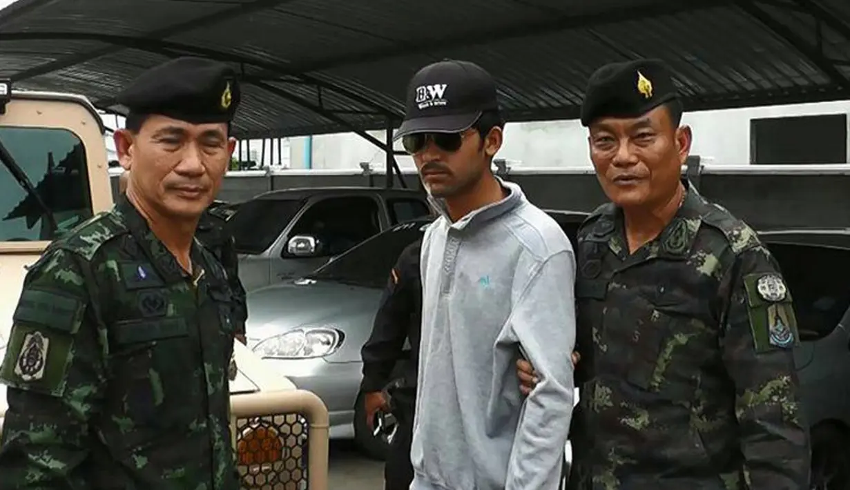Petugas Royal Thai Army bersama seorang tersangka yang diduga terlibat pengeboman Kuil Erawan, Bangkok, yang ditangkap di sebuah pos pemeriksaan di perbatasan Kamboja, Selasa (1/9/2015). (AFP Photo)