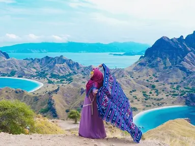 Perempuan yang memiliki channel youtube dengan subscriber 16,8 juta sampai sekarang ini tampak bahagia saat liburan di Labuan Bajo. Menggunakan pakaian serba ungu dan merah, ia memegang kain khas nusantara dengan lepas. (Liputan6.com/IG/@riaricis1795)