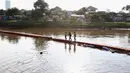 Anak-anak melintasi jembatan yang ada di Kanal Banjir Barat, Jakarta, Jumat (23/3). Selain mahalnya sewa kolam renang, berenang Kanal Banjir Barat dipilih anak-anak tersebut karena minimnya lahan bermain. (Liputan6.com/Immanuel Antonius)