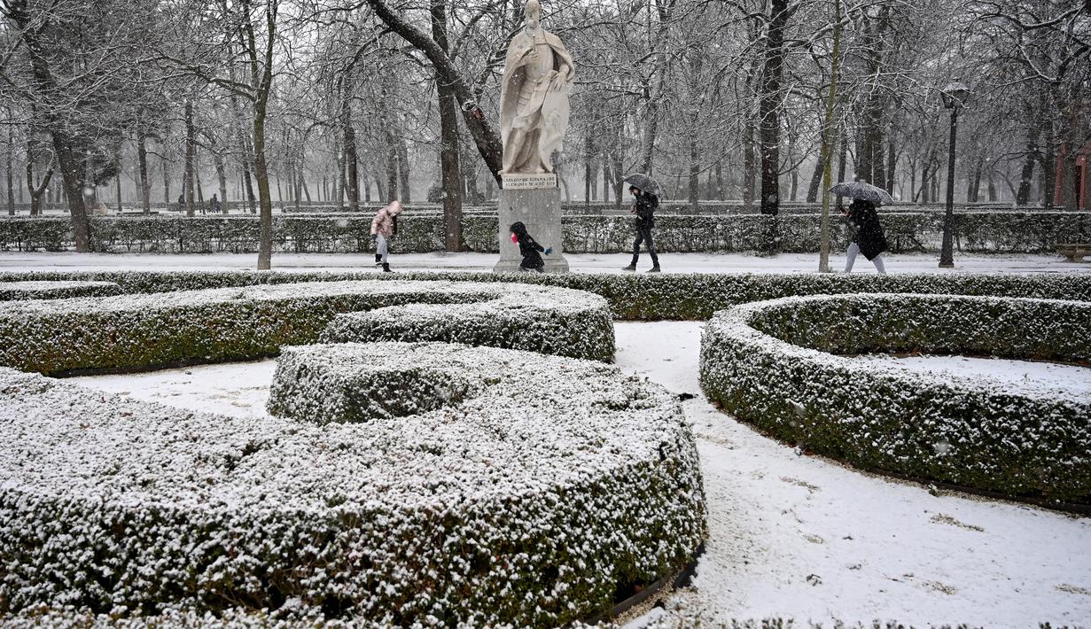 Orang-orang berjalan saat salju turun di Taman Retiro di pusat kota Madrid (7/1/2021). Spanyol dalam keadaan siaga cuaca untuk suhu dingin, es, hujan dan salju akibat Badai Filomena, yang diperkirakan akan melanda sebagian besar semenanjung Iberia dalam beberapa hari mendatang. (AFP/Gabriel Bouys)