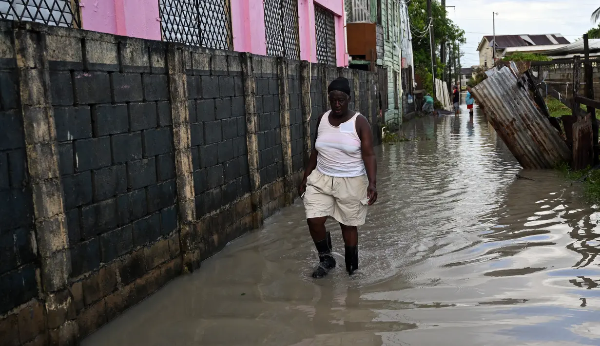 Seorang wanita berjalan melalui jalan yang banjir setelah Badai Lisa di Belize City, Belize, 3 November 2022. Badai Tropis Lisa menyebabkan banjir dan membuat sebagian negara itu menjadi gelap gulita. (Johan ORDONEZ/AFP)