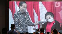 Ketua Umum PDIP Megawati Soekarnoputri (kanan) mengangkat tumpeng pemberian Presiden Joko Widodo atau Jokowi (kiri) saat Rakernas II PDIP di Jakarta, Selasa (21/6/2022). Rakernas PDIP kali ini mengusung tema 'Desa Kuat, Indonesia Maju dan Berdaulat'. (Liputan6.com/Faizal Fanani)