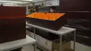 Seorang pekerja memindahkan peti mati kertas di pabrik LifeArt di Hong Kong pada Jumat, 18 Maret 2022. Hong Kong kehabisan peti mati selama wabah paling mematikan dari pandemi virus corona covid-19. (AP Photo/Kin Cheung)