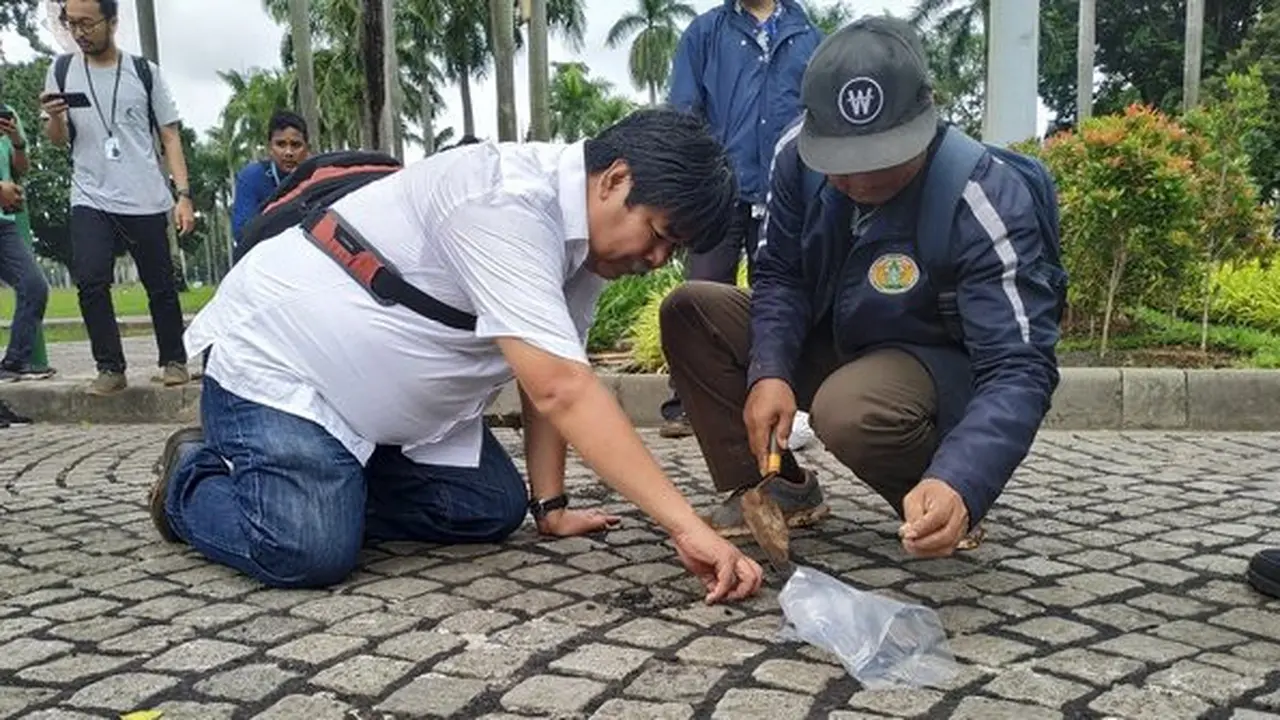 Petugas memperhatikan bekas aspal di Monas. (Merdeka.com/Yunita Amalia)