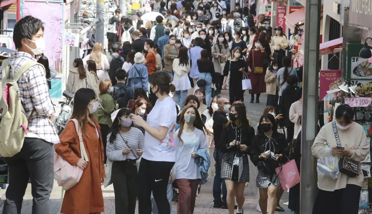 Orang-orang yang memakai masker wajah untuk melindungi dari penyebaran virus corona berjalan di sebuah jalan di Tokyo, Rabu (31/3/2021).  Ibukota Jepang mengonfirmasi lebih dari 410 kasus virus corona baru pada hari Rabu. (AP Photo/Eugene Hoshiko)