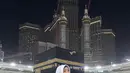 Berfoto di depan Ka'bah, Fuji mengenakan gamis dan kerudung putih yang dipermanis dengan bros. [Instagram/@fuji_an]