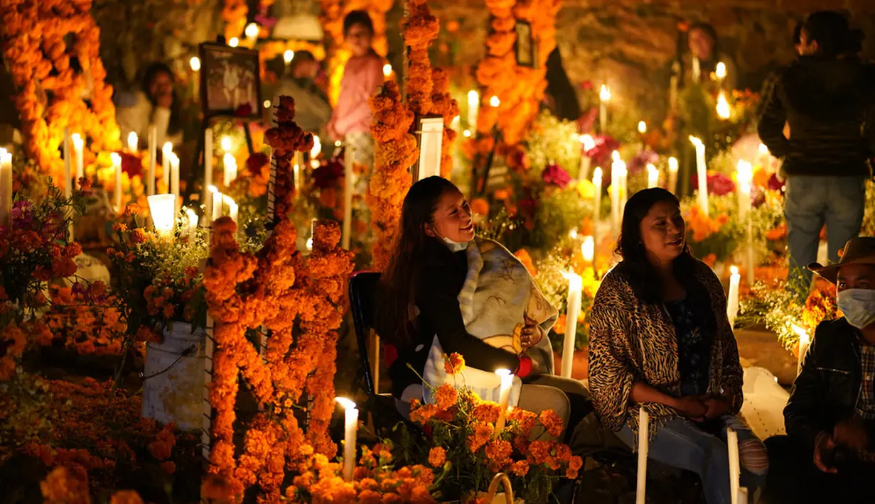 Kerabat menghabiskan malam di samping makam orang tercinta pada perayaan Hari Kematian di pemakaman Arocutin, Michoacan, Meksiko, 1 November 2021. Tradisi ini bertepatan dengan Hari Semua Orang Kudus dan Hari Semua Jiwa. (AP Photo/Eduardo Verdugo)