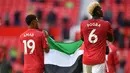 Gelandang Manchester United (MU), Amad Diallo (kiri) dan Paul Pogba mengibarkan bendera Palestina usai ditahan imbang Fulham pada pekan ke-37 Liga Inggris di Stadion Old Trafford, Rabu (19/5/2021) dinihari WIB. Pogba tampak diberikan bendera Palestina oleh seorang pendukung MU. (Paul ELLIS/POOL/AFP)