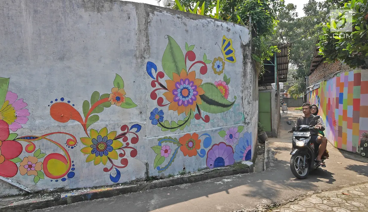 Pengendara motor melintasi gang sempit yang sisi tembok dindingnya dihiasi lukisan mural warna-warni di Kampung Pejaten, Jakarta, Senin (30/4). Mural motif warna-warni itu digagas warga untuk memperindah kampung mereka. (Liputan6.com/Herman Zakharia)