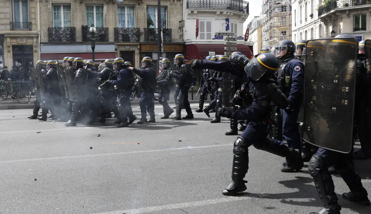 Polisi anti huru hara Prancis melemparkan tabung gas air mata ke arah pengunjuk rasa perayaan May Day di Paris, Senin (1/5). Seorang perwira polisi Prancis mengalami luka bakar dan dua lainnya luka-luka dalam bentrokan tersebut. (Zakaria ABDELKAFI/AFP)