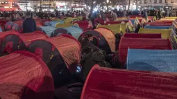 Aktivitas para migran di tenda yang mereka dirikan di Republic square, pusat kota Paris, pada Kamis (25/3/2021). Hampir 400 tenda didirikan di alun-aun tersebut untuk menarik perhatian atas kondisi kehidupan mereka dan menuntut akomodasi. (AP Photo/Rafael Yaghobzadeh)