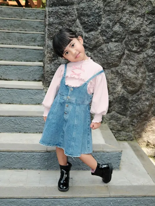 Tampilan manis lainnya dari Chava, ia memadukan blus panjang warna pink pastel dengan overal denim dress. Penampilannya dilengkapi sepatu boots dan tatanan rambut bun pigtails. [@rachelvennya].