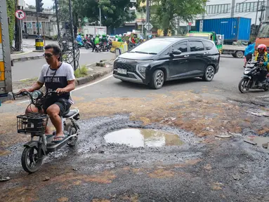 Pengendara menghindari kerusakan di Jalan Mitra Bahari, Penjaringan Jakarta Utara, Selasa (03/02/2026). Tingginya curah hujan yang mengguyur Jakarta berimbas pada rusaknya sejumlah ruas jalan. (merdeka.com/Arie Basuki)