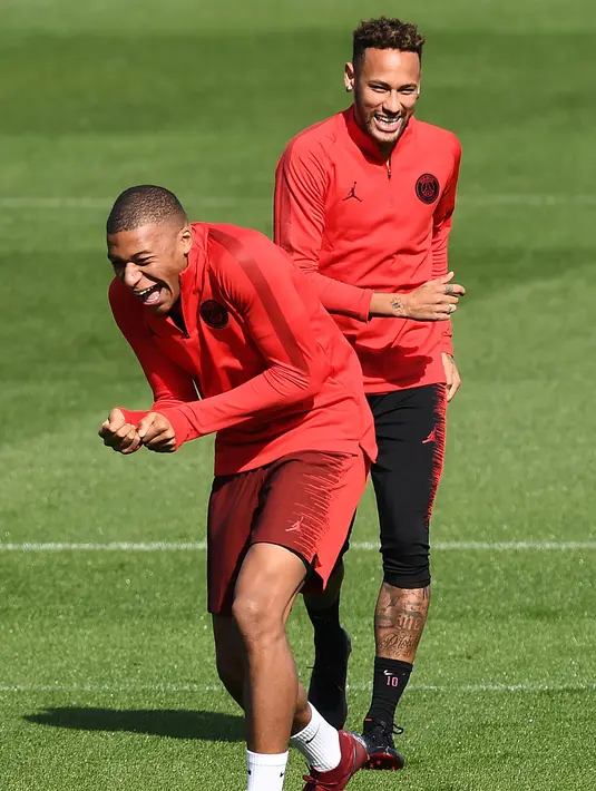 Pemain Paris Saint-Germain (PSG), Neymar (kanan) dan Kylian Mbappe (kiri) tertawa saat sesi latihan di Paris Barat, Prancis, Senin (17/9). PSG akan menghadapi Liverpool di Liga Champions pada 19 September 2018. (Anne-Christine POUJOULAT/AFP)